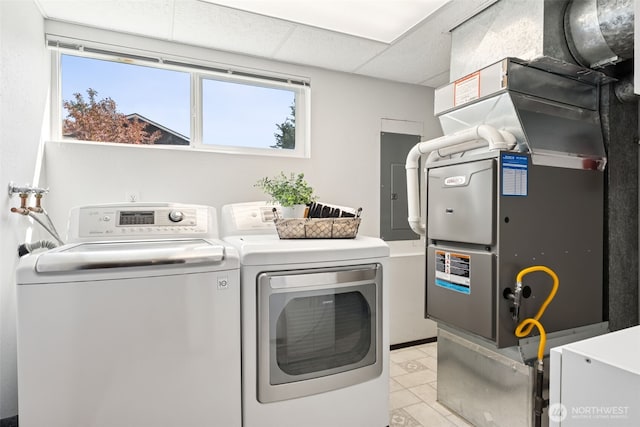 washroom with washing machine and clothes dryer, laundry area, heating unit, and a healthy amount of sunlight