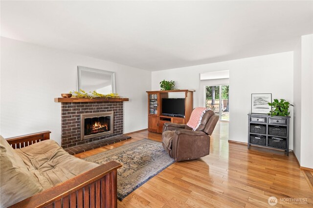 living room featuring light wood-style floors and a brick fireplace