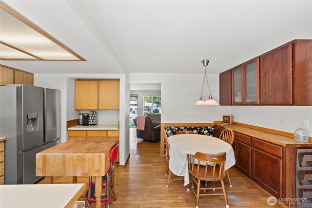 kitchen with stainless steel fridge, glass insert cabinets, light wood-style floors, and butcher block countertops