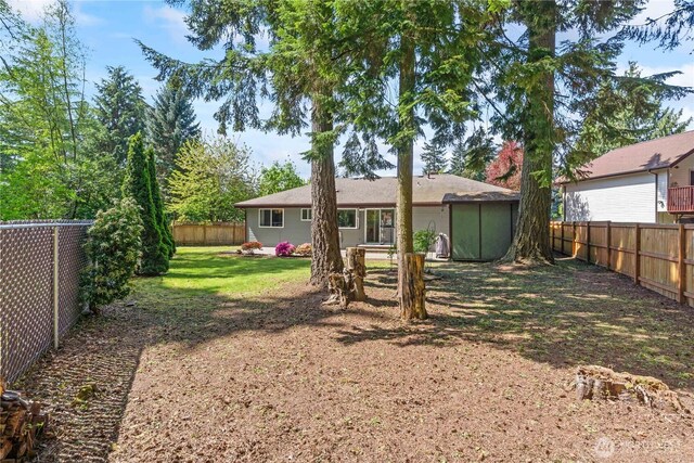 rear view of house featuring a fenced backyard and a yard
