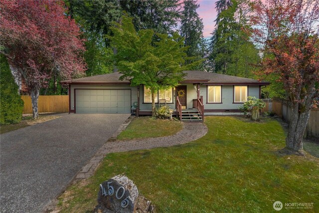 ranch-style home featuring fence, an attached garage, a front yard, and aphalt driveway