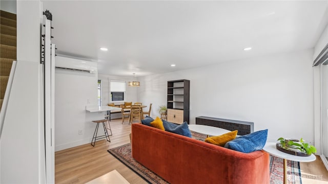 living area featuring an AC wall unit, recessed lighting, light wood-style flooring, and a barn door