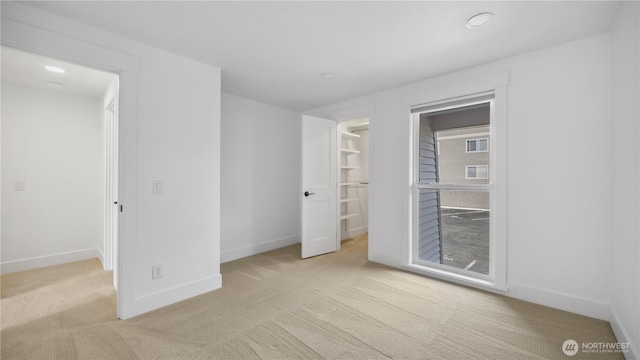 unfurnished bedroom with light colored carpet, recessed lighting, baseboards, and a spacious closet