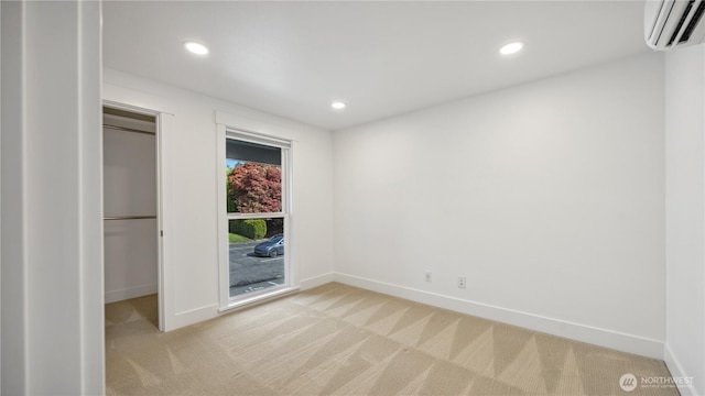 empty room featuring recessed lighting, baseboards, light carpet, and a wall mounted air conditioner