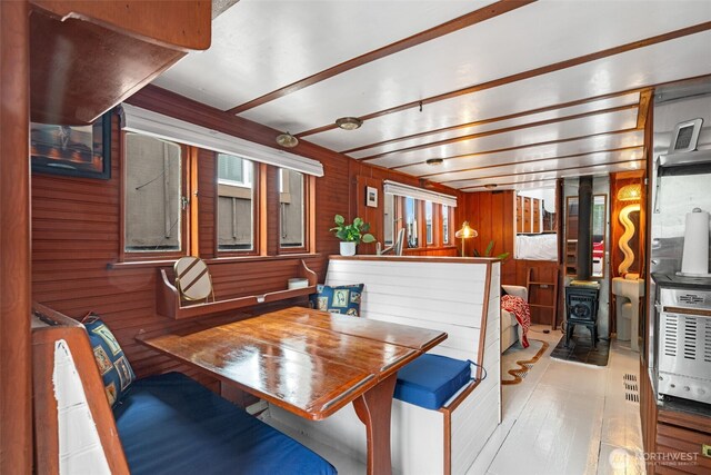 dining space featuring wood walls, wood finished floors, and a wood stove