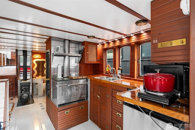 kitchen with a wood stove, a sink, stainless steel microwave, and brown cabinets