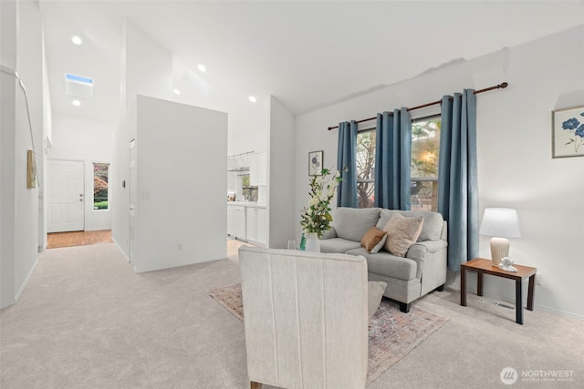 living room with baseboards, high vaulted ceiling, and light carpet