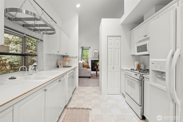 kitchen featuring white appliances, light floors, light countertops, white cabinets, and a sink