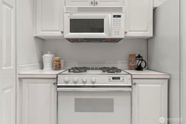 kitchen with light countertops, white cabinets, and white appliances
