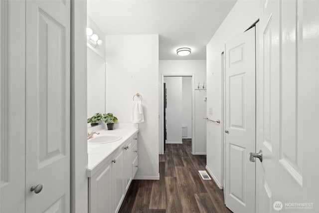 bathroom with baseboards, visible vents, wood finished floors, and vanity