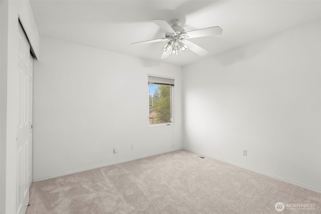 carpeted empty room featuring visible vents, baseboards, and ceiling fan
