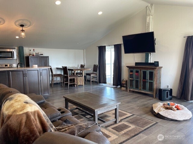 living room with recessed lighting, wood finished floors, and vaulted ceiling