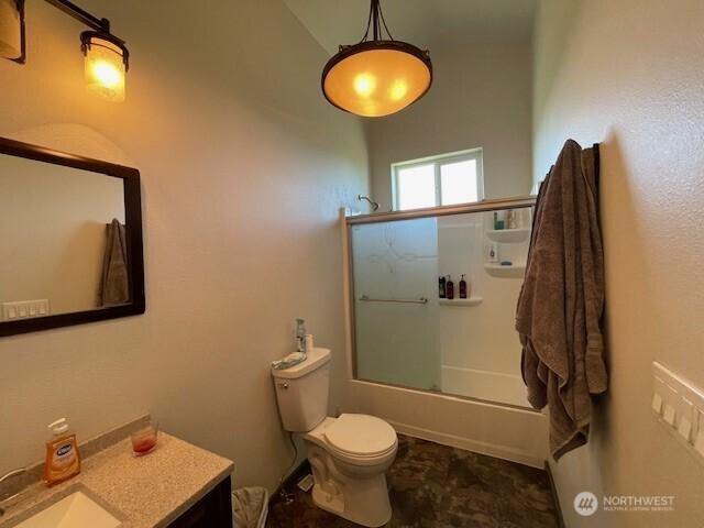 bathroom featuring vanity, combined bath / shower with glass door, and toilet