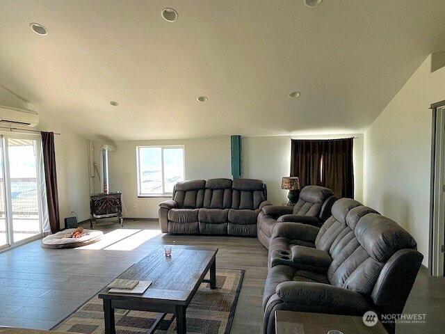 living area with lofted ceiling, a wood stove, and a wall mounted air conditioner