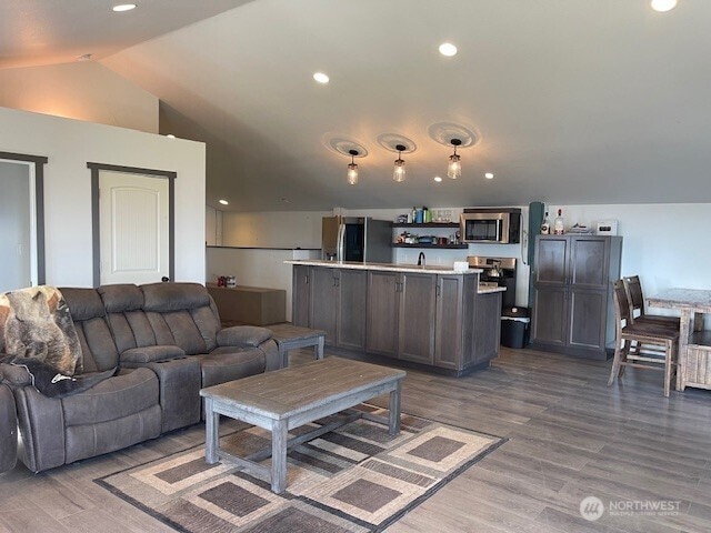 living room featuring vaulted ceiling, recessed lighting, and wood finished floors
