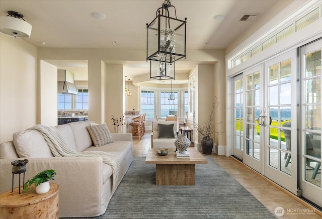5848 Mutiny Bay Rd, Freeland, WA 98249 - living room with visible vents, wood finished floors, baseboards, a chandelier, and french doors