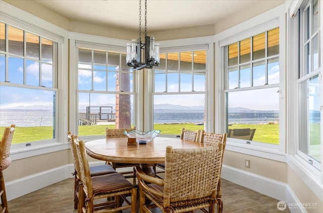 5848 Mutiny Bay Rd, Freeland, WA 98249 - dining room featuring baseboards, a water view, wood finished floors, and a notable chandelier
