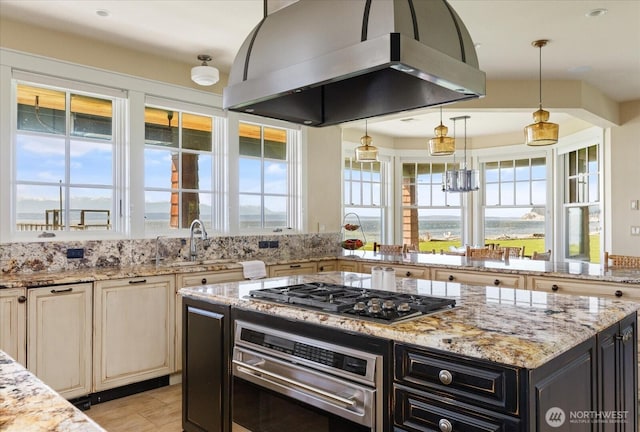 5848 Mutiny Bay Rd, Freeland, WA 98249 - kitchen with island range hood, dark cabinets, cream cabinetry, light stone counters, and stainless steel appliances