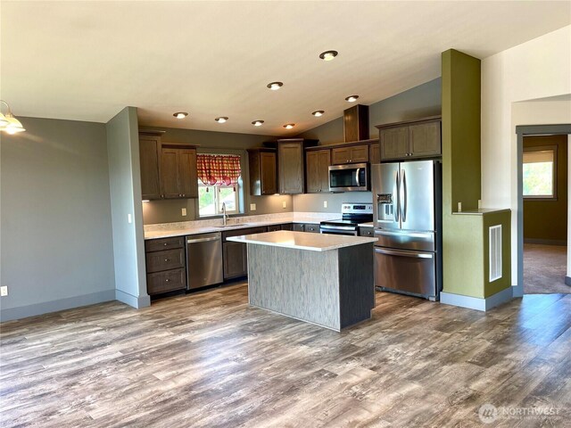 415 Olympic View Dr NE, Ocean Shores, WA 98569 - kitchen with stainless steel appliances, light countertops, wood finished floors, a kitchen island, and lofted ceiling