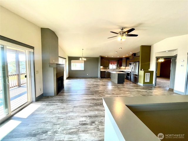 415 Olympic View Dr NE, Ocean Shores, WA 98569 - kitchen with stainless steel fridge, baseboards, open floor plan, a ceiling fan, and vaulted ceiling