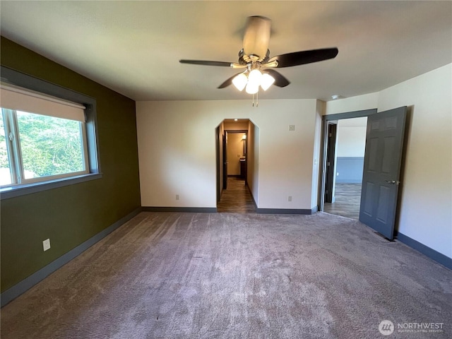 415 Olympic View Dr NE, Ocean Shores, WA 98569 - unfurnished bedroom featuring carpet floors, arched walkways, baseboards, and a ceiling fan