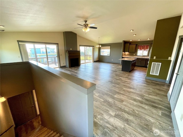 415 Olympic View Dr NE, Ocean Shores, WA 98569 - unfurnished living room with vaulted ceiling, ceiling fan, wood finished floors, a sink, and baseboards