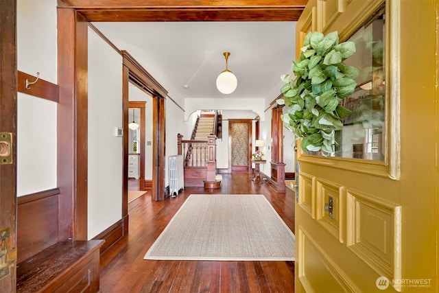 interior space featuring wood finished floors, radiator, and stairs