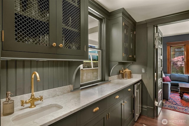bar with beverage cooler, a sink, dark wood-type flooring, and a healthy amount of sunlight