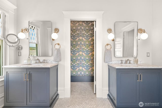 full bathroom with baseboards, two vanities, and a sink