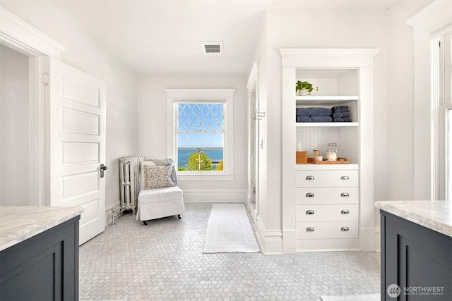 living area featuring baseboards, visible vents, and radiator