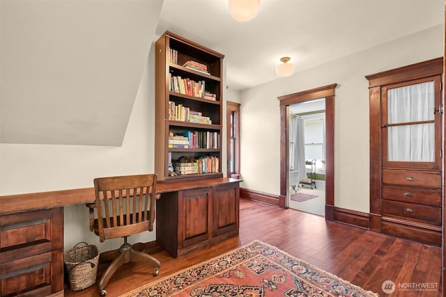 office area featuring baseboards, dark wood finished floors, and built in desk