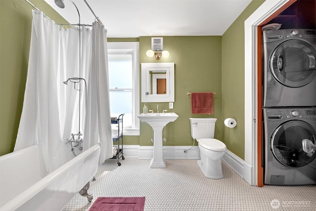 bathroom with stacked washer and dryer, toilet, visible vents, and baseboards