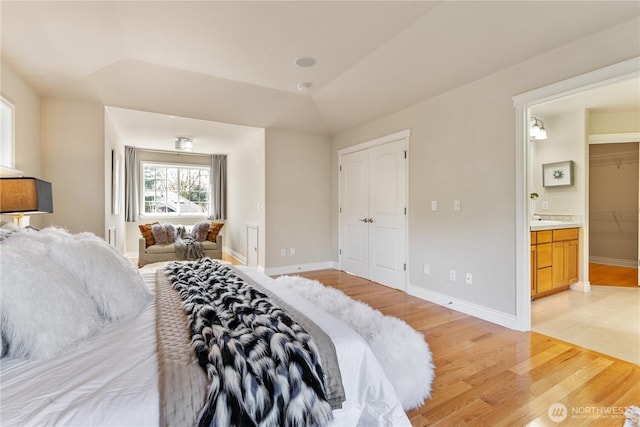 13914 SE 88th Pl, Newcastle, WA 98059 - bedroom featuring a sink, baseboards, ensuite bathroom, light wood-type flooring, and a tray ceiling