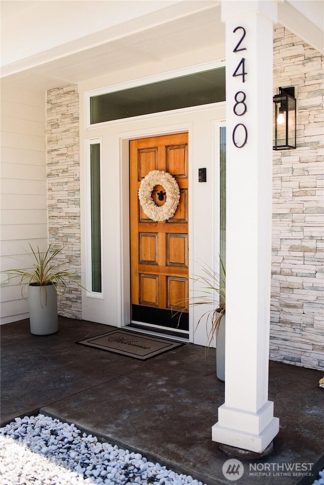 doorway to property with covered porch and stone siding