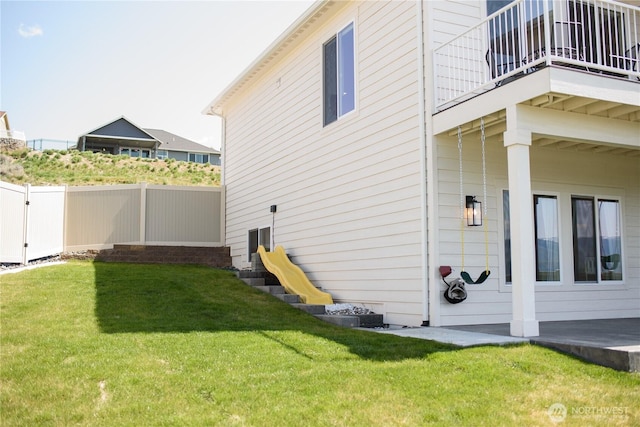 view of property exterior featuring a lawn, fence, and a balcony
