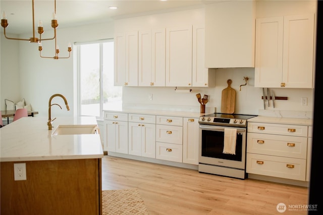 kitchen with electric stove, a sink, a notable chandelier, and white cabinets