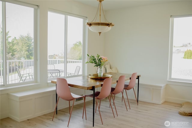 dining space with light wood-style floors, a wainscoted wall, and a decorative wall