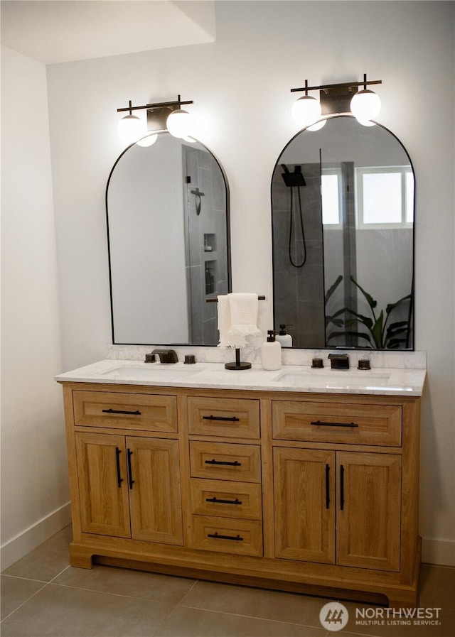 full bath with double vanity, baseboards, tile patterned flooring, and a shower