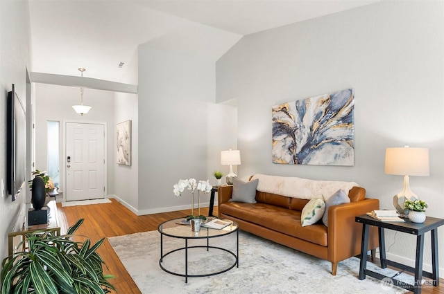 living area with baseboards, lofted ceiling, and wood finished floors