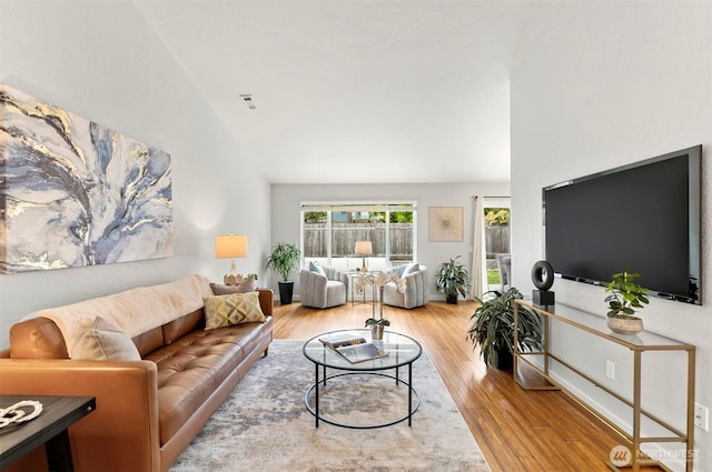 living area with vaulted ceiling, wood finished floors, and visible vents
