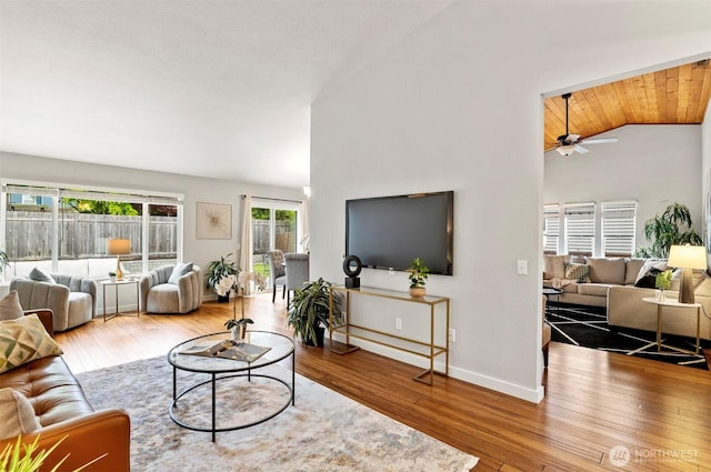 living area featuring baseboards, wood-type flooring, a ceiling fan, and lofted ceiling