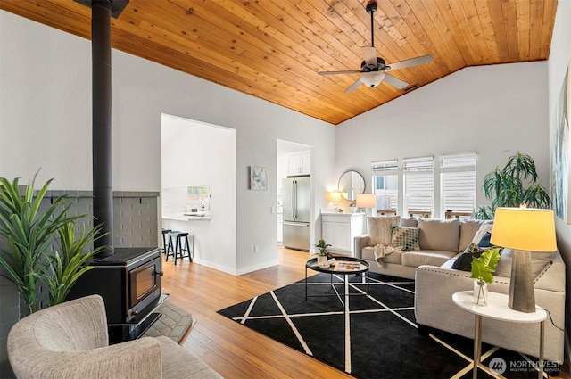 living room featuring ceiling fan, a wood stove, high vaulted ceiling, wooden ceiling, and light wood-type flooring