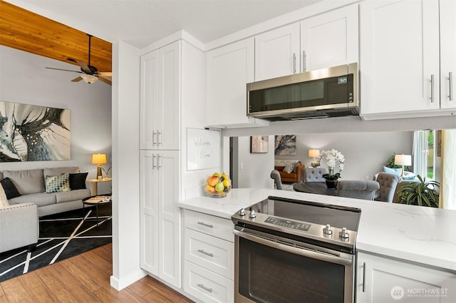 kitchen featuring white cabinetry, open floor plan, appliances with stainless steel finishes, and ceiling fan
