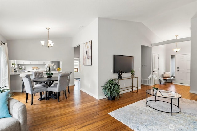 living area featuring light wood-type flooring, lofted ceiling, a chandelier, and visible vents