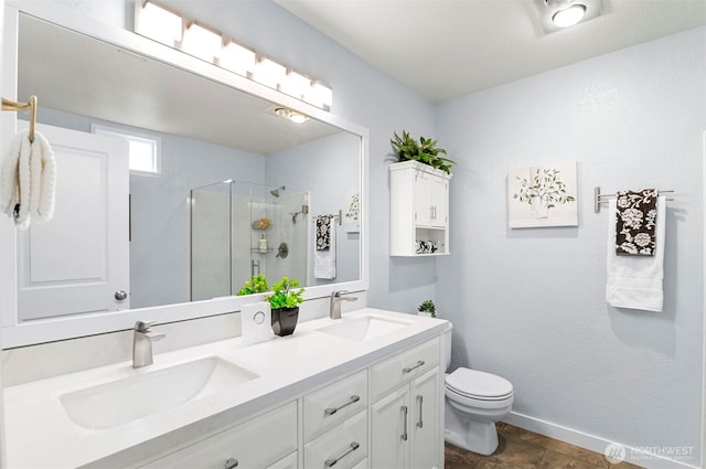 bathroom featuring double vanity, a sink, a stall shower, and toilet