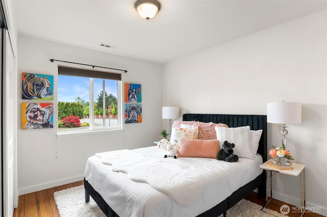 bedroom with baseboards, wood finished floors, and visible vents