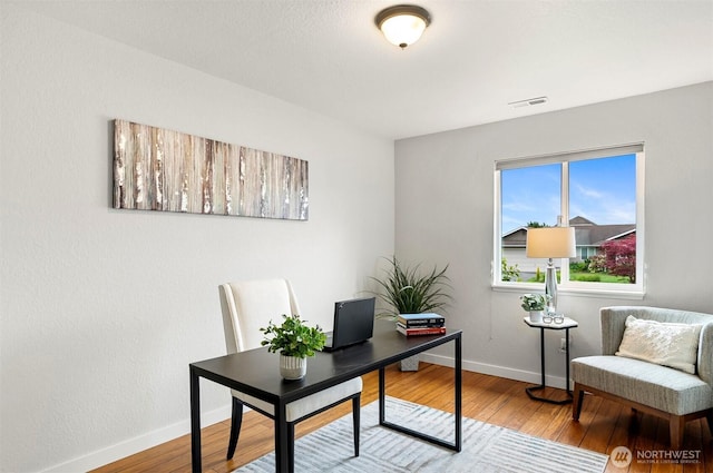 office area with baseboards, wood finished floors, and visible vents