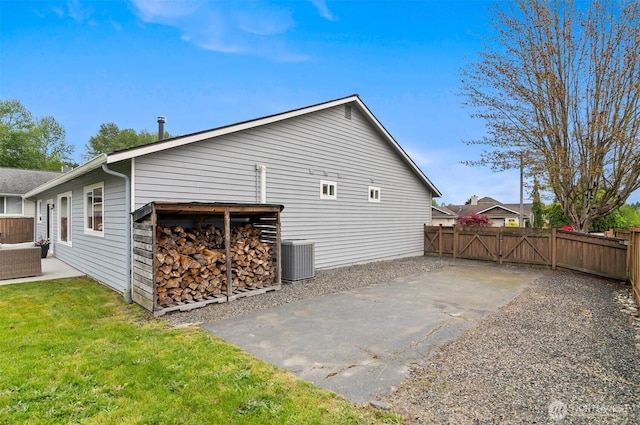 view of side of home with a gate, a patio area, central air condition unit, fence, and a yard