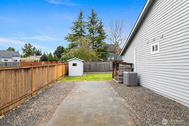 view of yard featuring a storage unit, a patio, a fenced backyard, central AC unit, and an outdoor structure