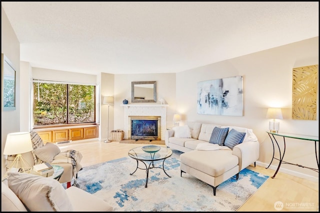 living room with a glass covered fireplace, baseboards, wood finished floors, and visible vents